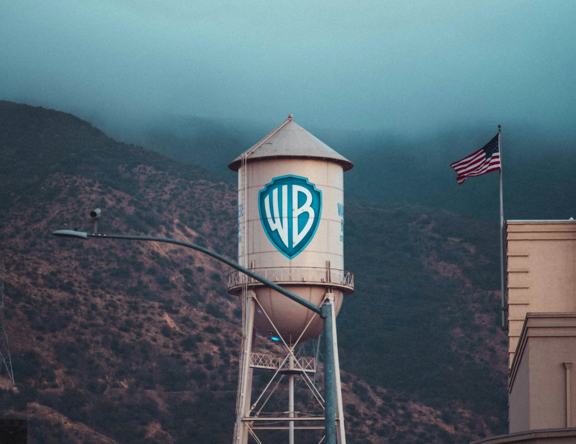 a water tower with a sign on it in front of a mountain